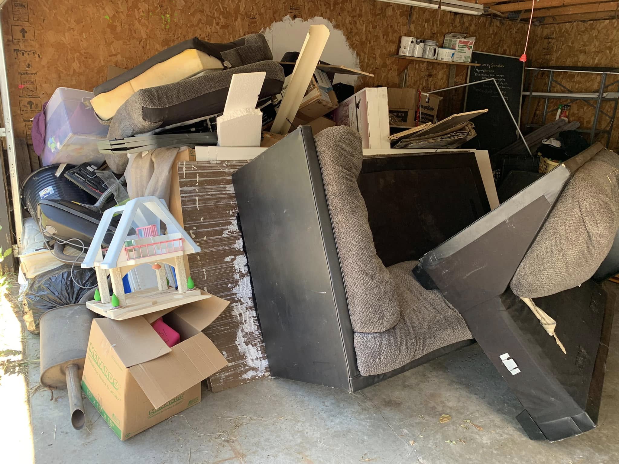 A garage packed with sofas, mattresses, recliners, and household furniture — a typical full-house furniture cleanout for WeHaul