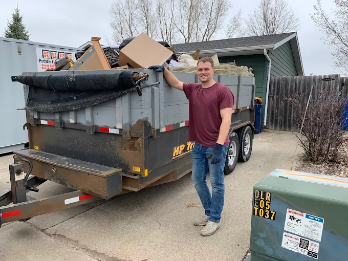 WeHaul team member next to a fully loaded dump trailer of junk in Sioux Falls, SD — ready to haul